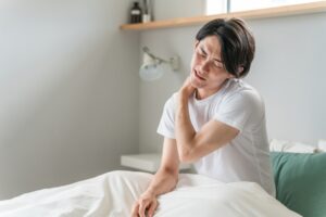 朝起きて首の痛みに悩んでいる男性