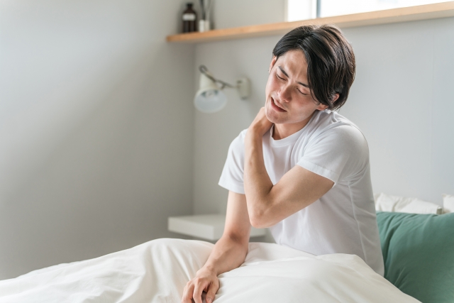 朝起きて首の痛みに悩んでいる男性