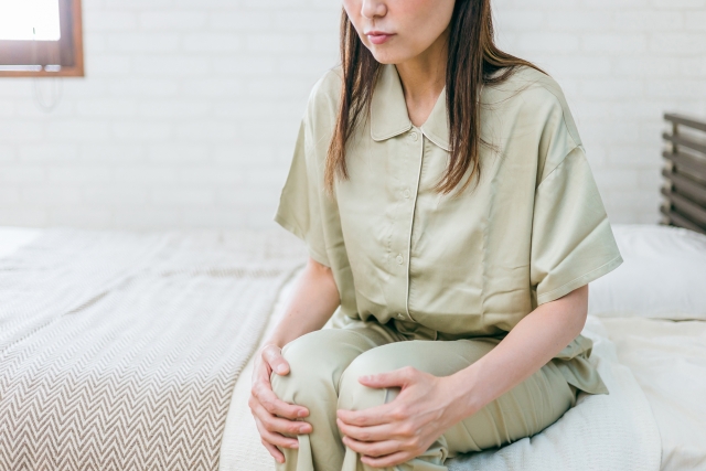 朝起きて膝のこわばりを感じている女性